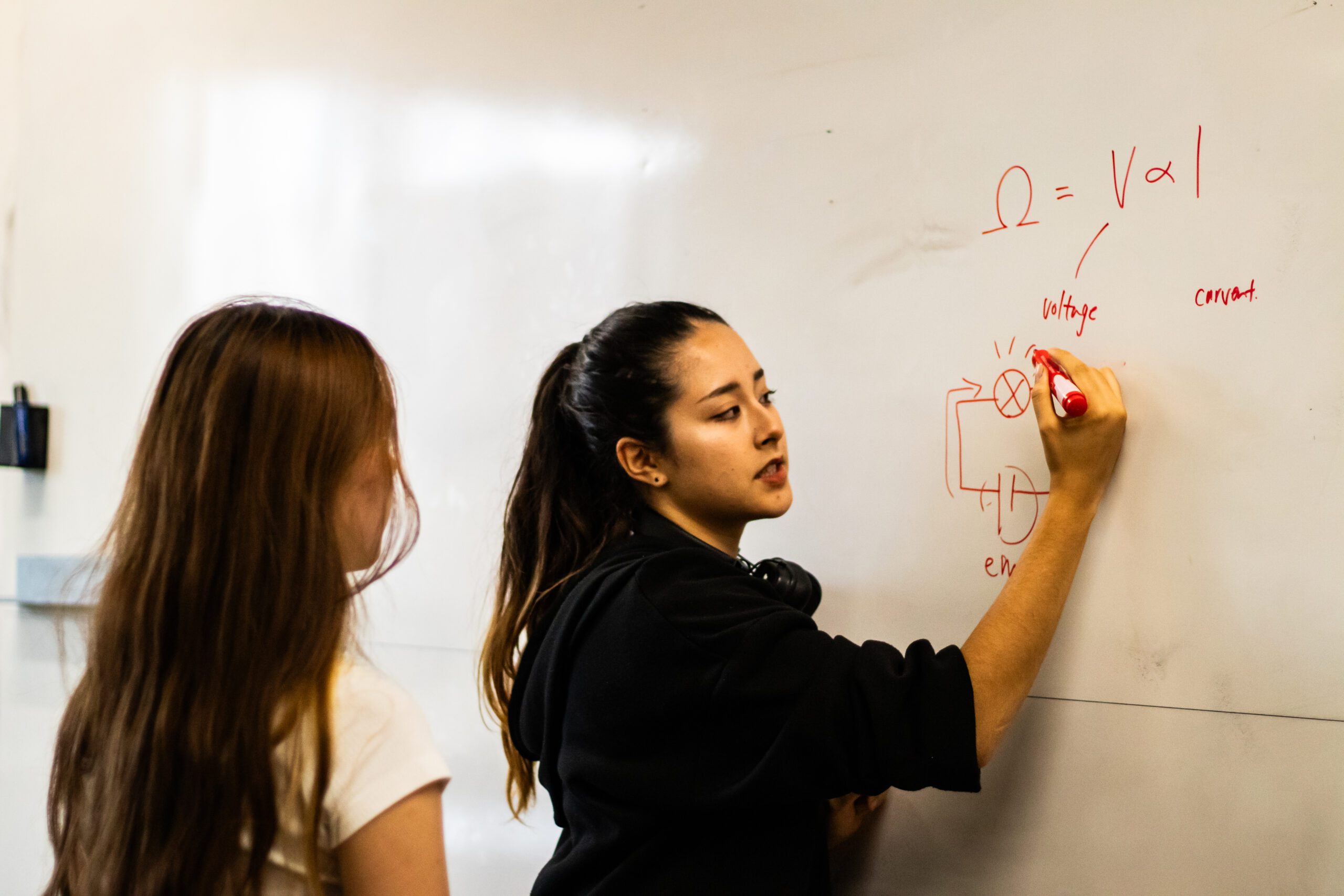 DP students working on a physics equation on the whiteboard