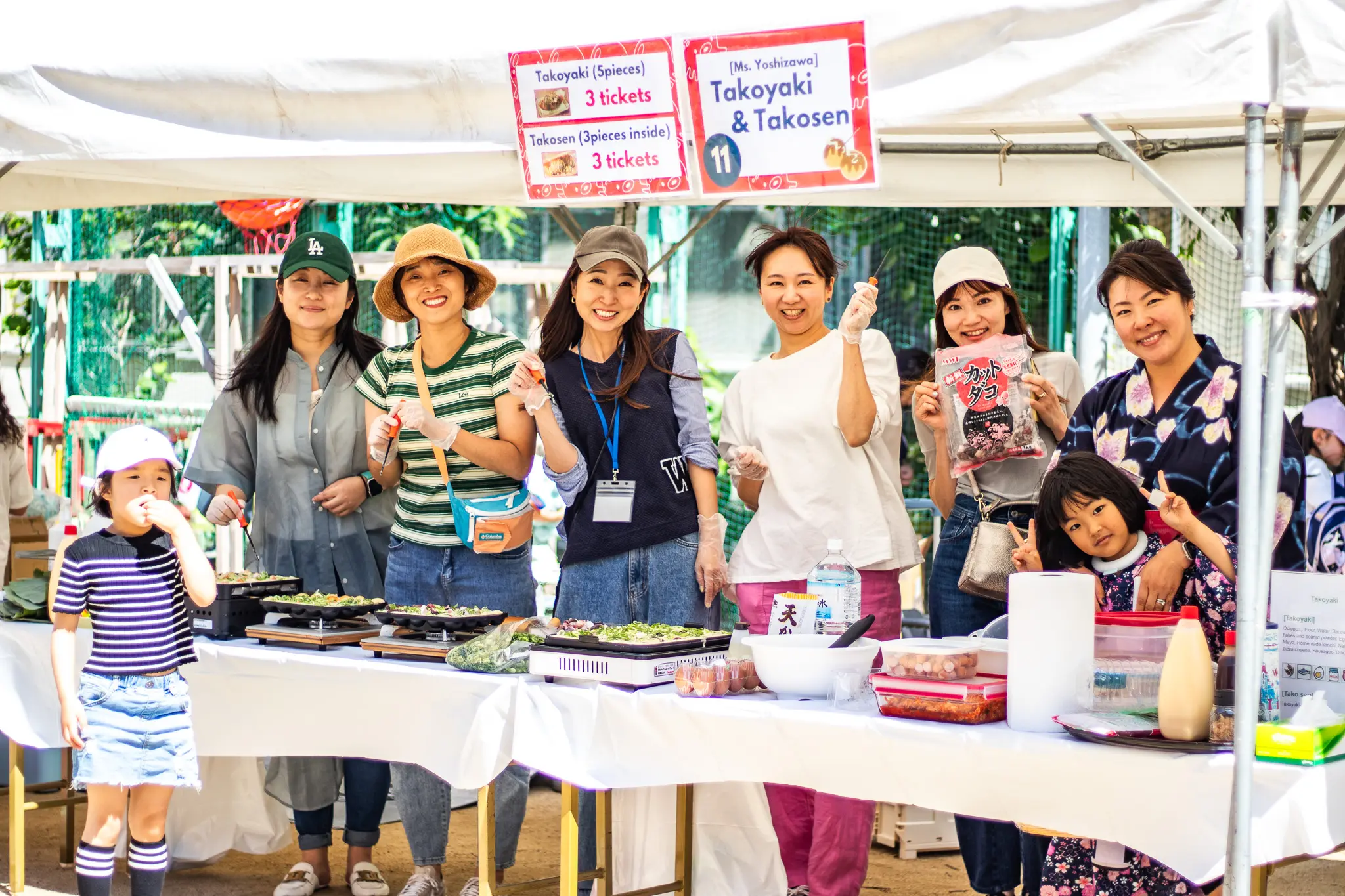 The Parent Volunteer Group (PVG) waving hello from their takoyaki table at the school festival