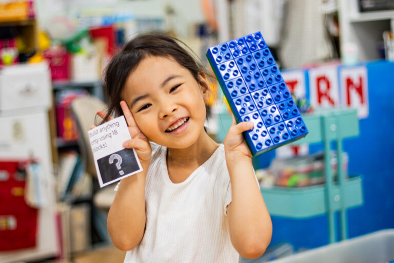 A kindergarten student shows off their counting skills with lego blocks